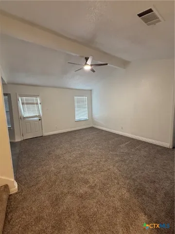 an empty room with chandelier fan and windows