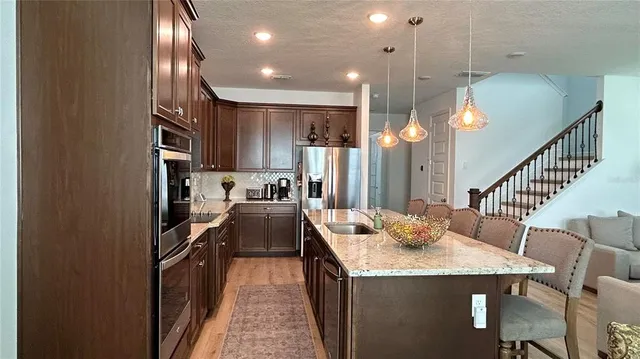 a kitchen with stainless steel appliances granite countertop a table chairs refrigerator and sink