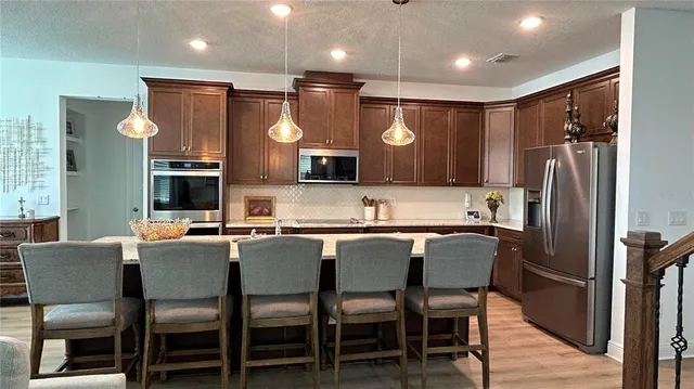 a kitchen with stainless steel appliances granite countertop a sink refrigerator and cabinets