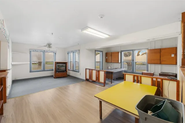 a large white kitchen with a refrigerator a stove a wooden floor and a sink