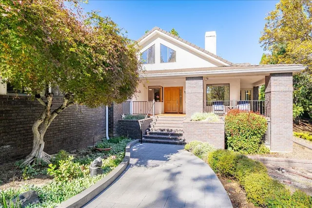 a front view of a house with a yard and potted plants