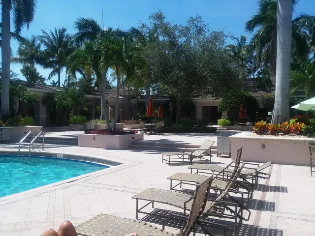 a view of a swimming pool with lawn chairs under an umbrella