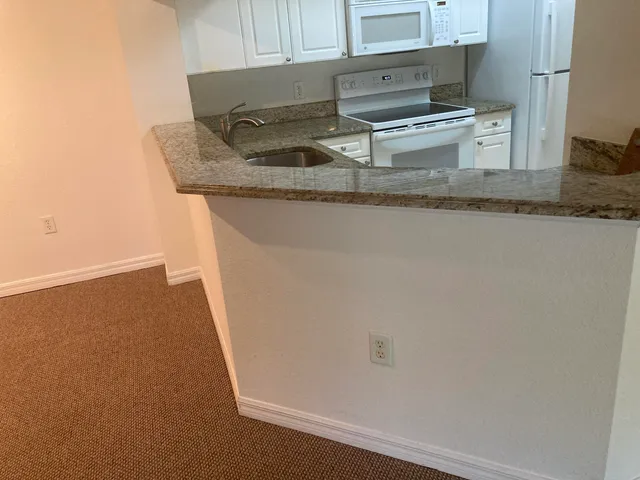 a view of an empty room with window and chandelier fan