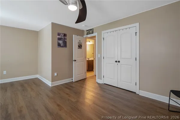 an empty room with wooden floor chandelier fan and windows