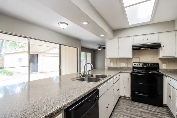 a kitchen with stainless steel appliances granite countertop a sink a stove and a wooden floors