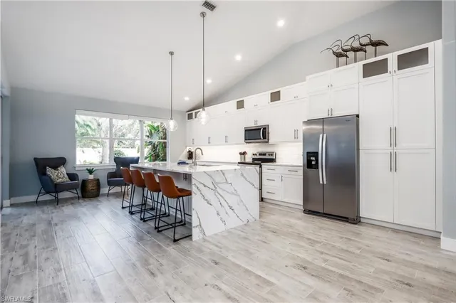 a kitchen with stainless steel appliances a refrigerator a stove a sink dishwasher with a dining table and chairs with wooden floor