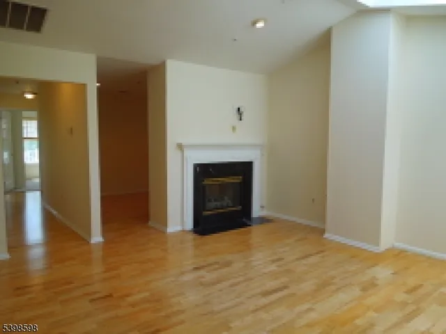 a view of an empty room with wooden floor and a fireplace