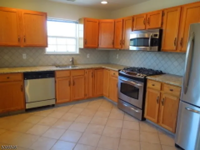 a kitchen with granite countertop a stove top oven microwave and cabinets