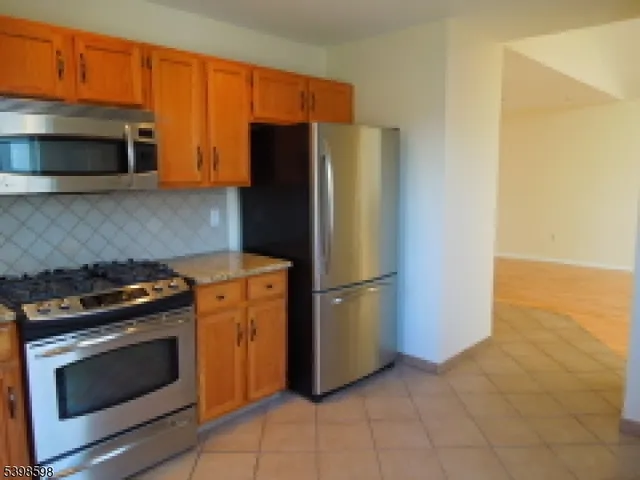 a kitchen with granite countertop a stove microwave and refrigerator