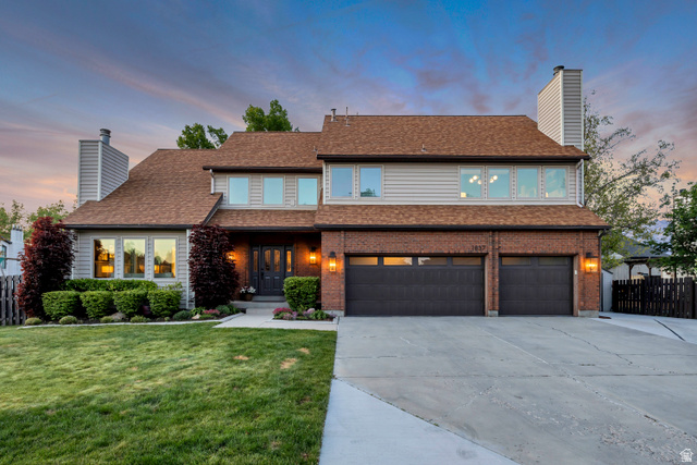 1837 Richard Road Sandy, UT 84093 - Photo 6 of 67 Traditional-style residence featuring a two-car garage with carriage-style doors, brick and siding facade, multiple windows, and a separate walk-out basement with a 2-bedroom apartment.