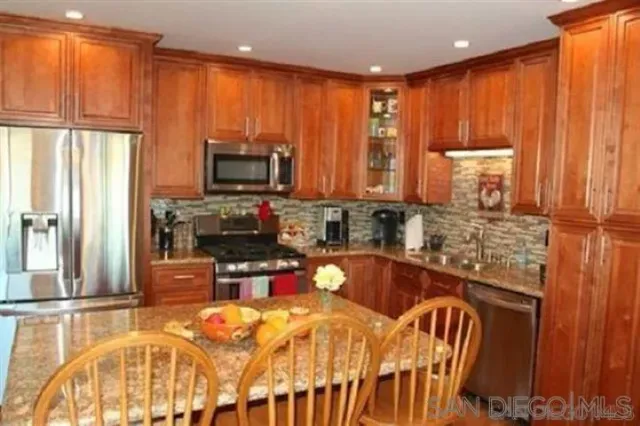 a kitchen with stainless steel appliances wooden cabinets a stove top oven a sink and a refrigerator