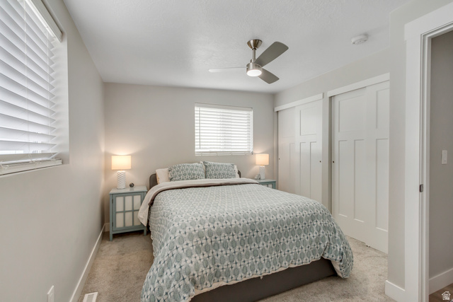 48 Moon Ridge Drive Murray, UT 84107 - Photo 11 of 30 Carpeted bedroom featuring two windows with horizontal blinds, a ceiling fan with integrated lighting, and two sliding panel doors
