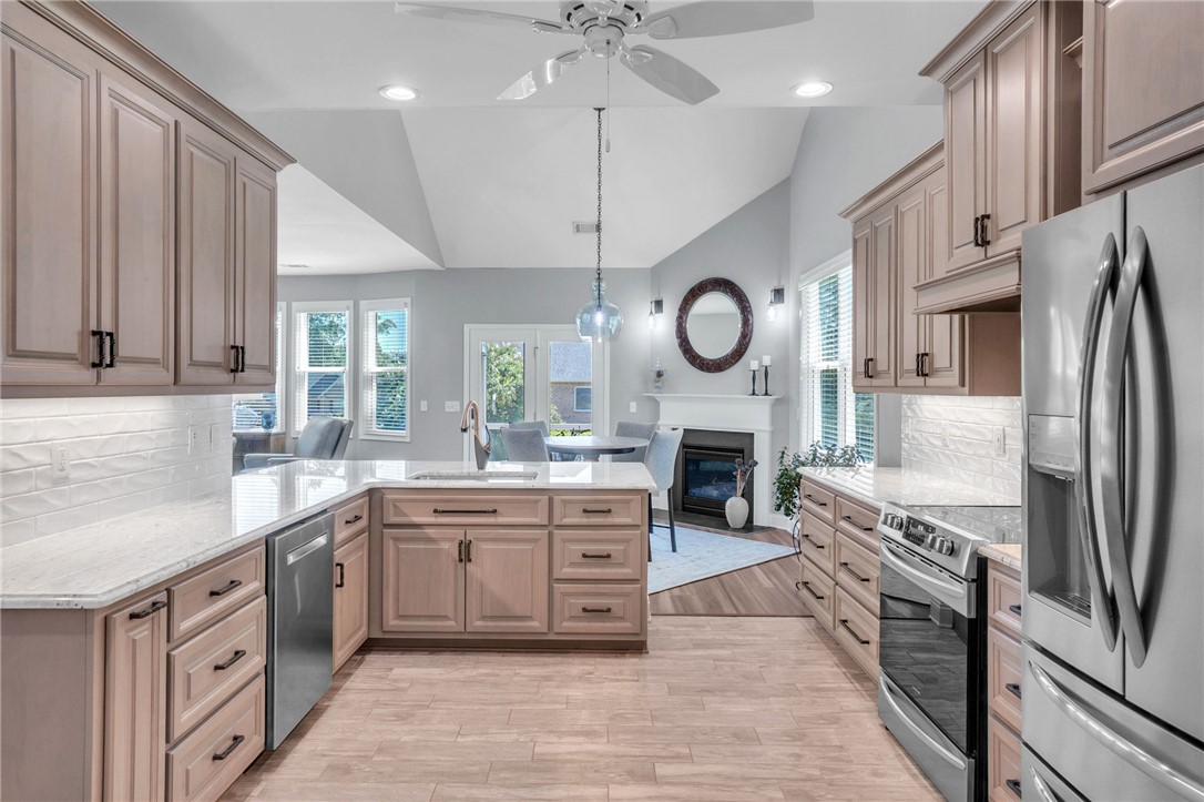 116 Stone Cottage Drive Anderson, SC 29621 - Photo 13 of 43 Vaulted ceilings and wood-look flooring enhance this open kitchen layout leading to a fireplace.