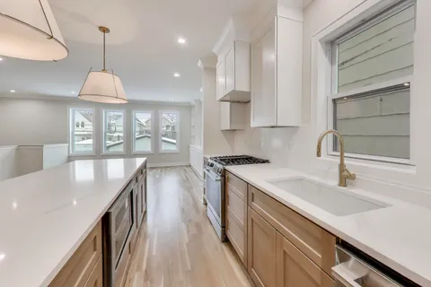 a kitchen with kitchen island a counter space a sink a stove and a refrigerator