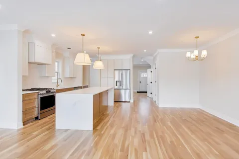 a large kitchen with granite countertop a large counter top a sink stainless steel appliances and cabinets