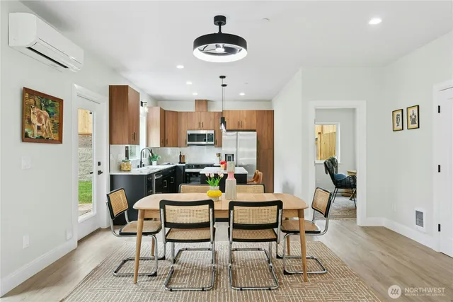 a dining room with stainless steel appliances kitchen island granite countertop a dining table chairs and a refrigerator