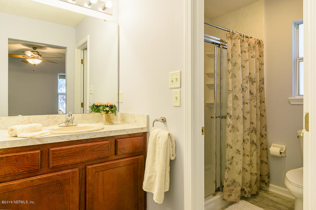 5491 Spring Brook Road Jacksonville, FL 32277 - Photo 9 of 29 a bathroom with a granite countertop sink a mirror a shower and a toilet