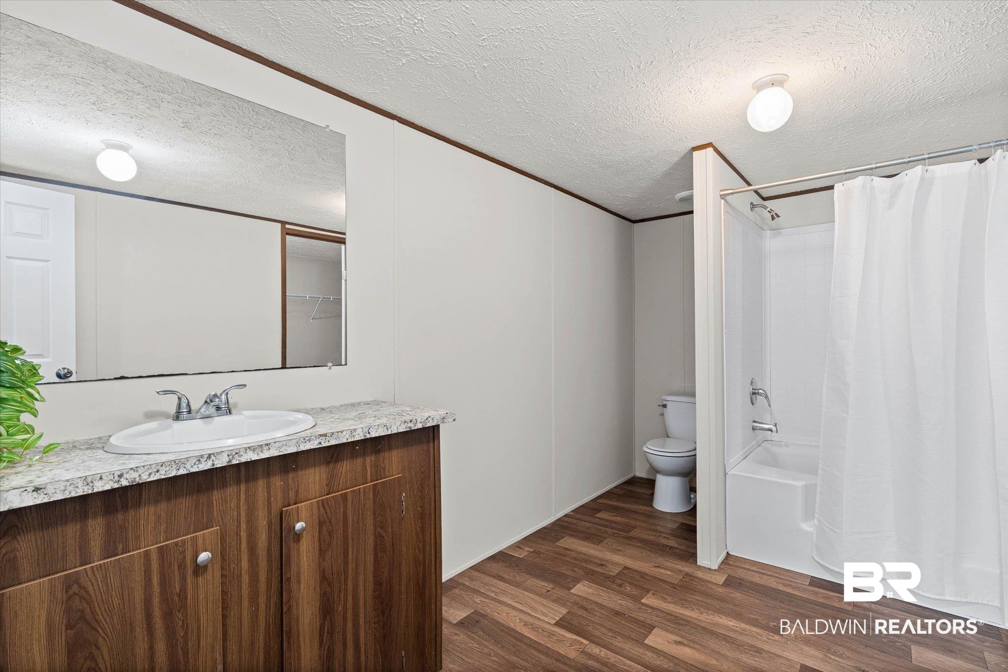 25366 Pollard Road Daphne, AL 36526 - Photo 14 of 22 Bathroom featuring a vanity with wood-finish cabinetry, a single basin sink, and a large wall-mounted mirror