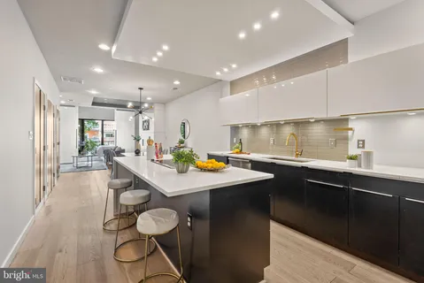 a kitchen with stainless steel appliances granite countertop a sink a stove a dining table and chairs