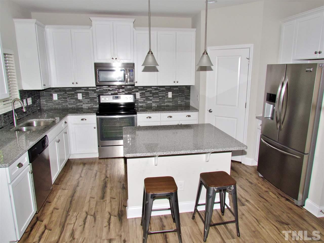 5713 Spring Glen Lane Raleigh, NC 27616 - Photo 8 of 25 a kitchen with stainless steel appliances granite countertop a refrigerator a stove a sink and white cabinets with wooden floor