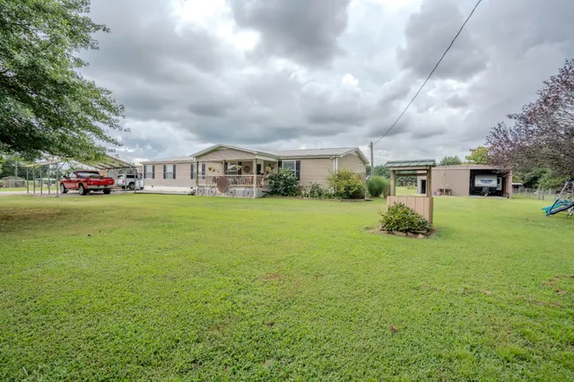a view of a house with a big yard and large trees