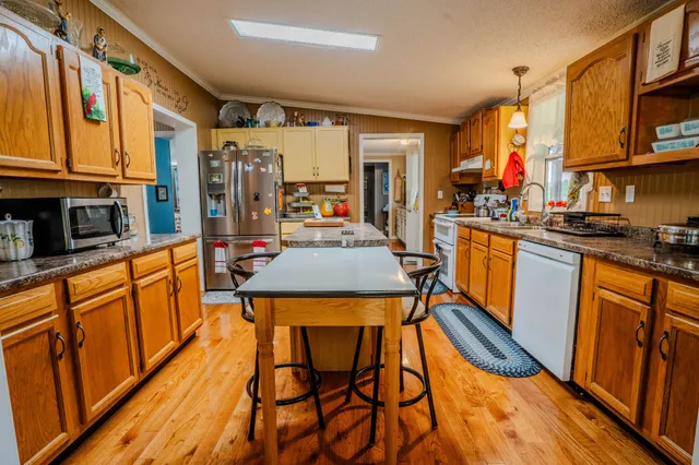 a kitchen with stainless steel appliances granite countertop table chairs stove and cabinets