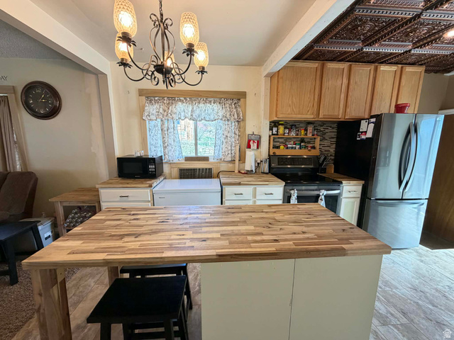 156 D Street Helper, UT 84526 - Photo 10 of 24 Kitchen featuring a chandelier, stainless steel appliances, a kitchen breakfast bar, wooden counters, and tasteful backsplash