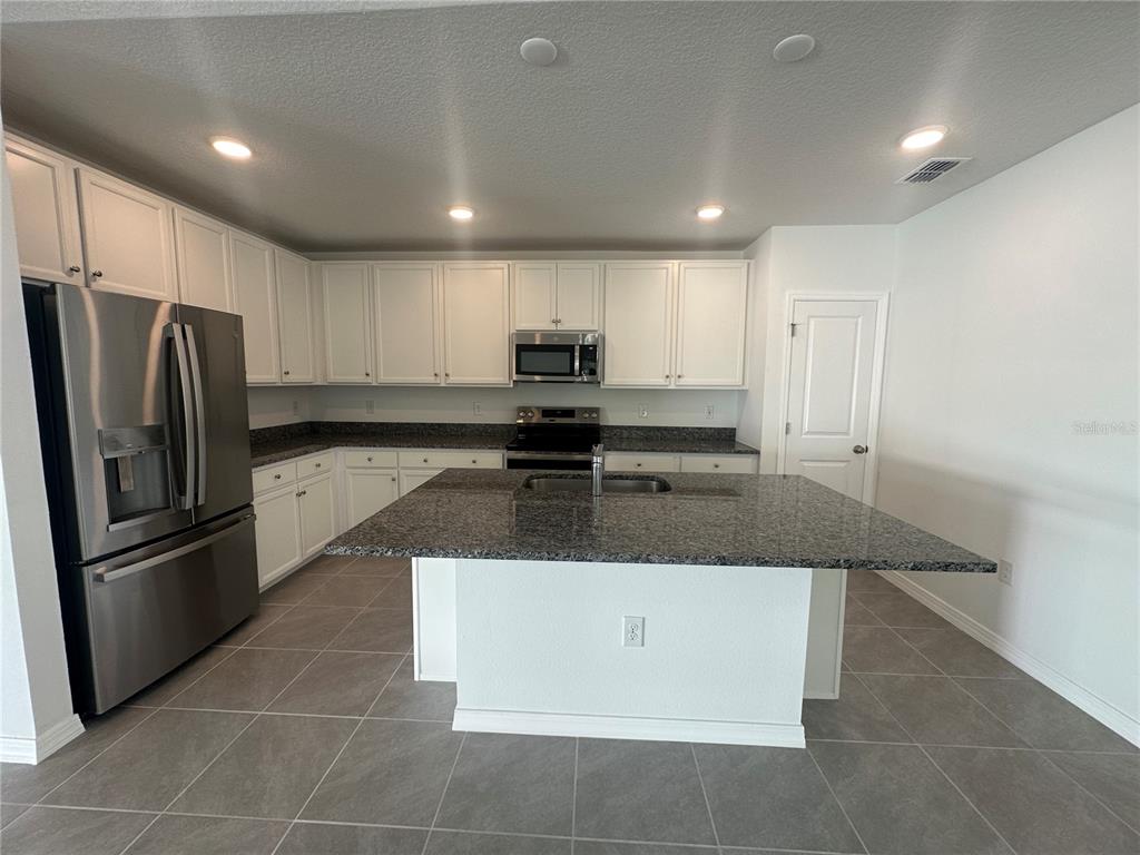 8795 Southwest 135th Place Ocala, FL 34473 - Photo 13 of 22 a large kitchen with stainless steel appliances granite countertop a sink a stove a refrigerator and a refrigerator