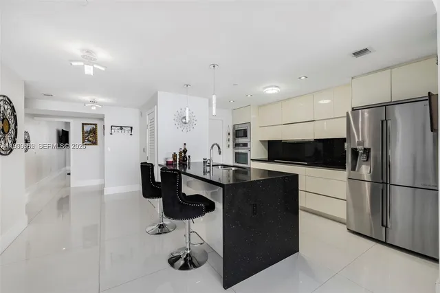 a kitchen with stainless steel appliances kitchen island granite countertop a refrigerator and a sink
