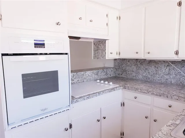 a kitchen with granite countertop white cabinets and white appliances