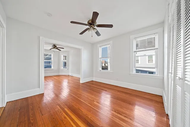 a view of empty room with wooden floor and ceiling fan