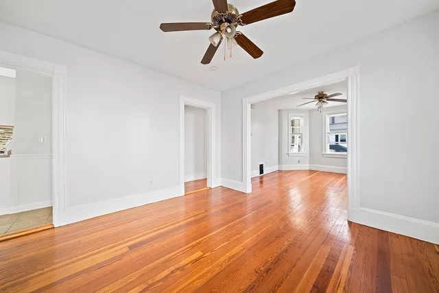a view of empty room with wooden floor and fan
