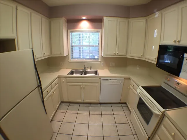 a kitchen with a sink a stove cabinets and a window
