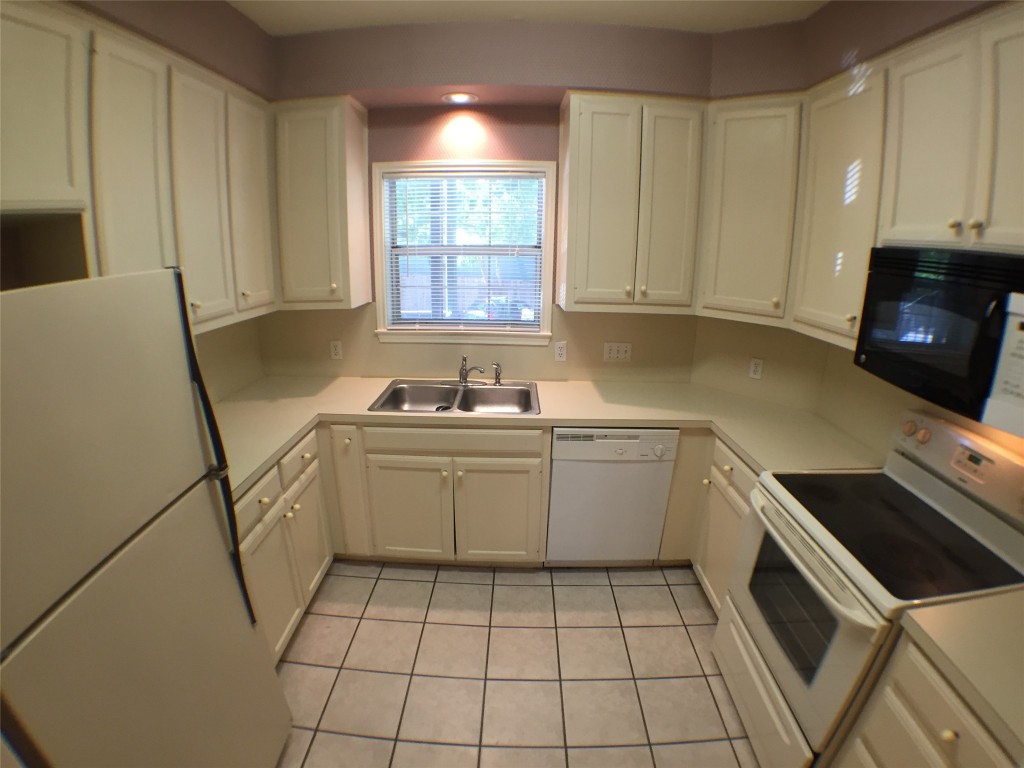 2100 San Gabriel Street, Unit 103 Austin, TX 78705 - Photo 6 of 20 a kitchen with a sink a stove cabinets and a window