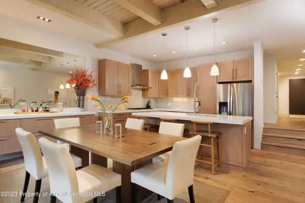 a dining room with stainless steel appliances granite countertop a table chairs and a refrigerator