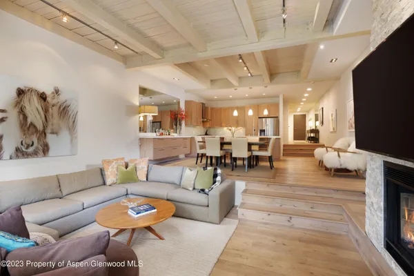 a living room with furniture kitchen view and a chandelier