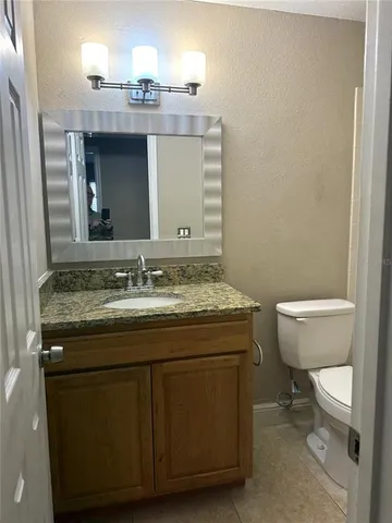 a bathroom with a granite countertop toilet a sink and a mirror