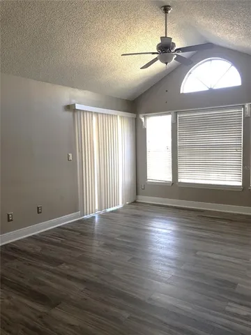 an empty room with wooden floor chandelier and windows