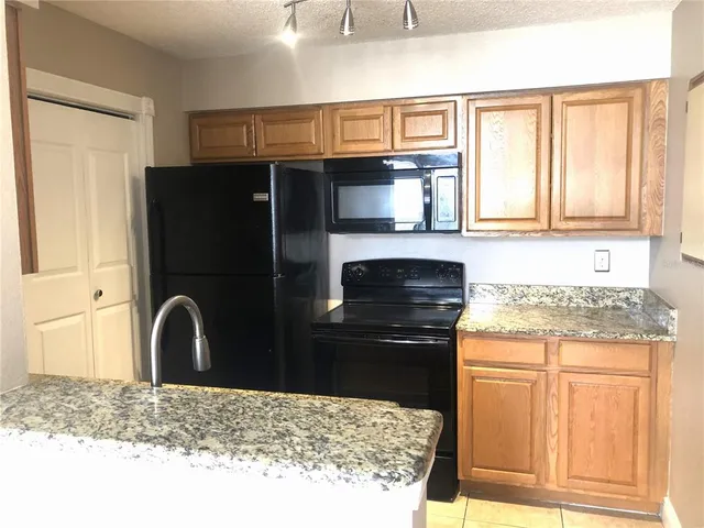 a kitchen with granite countertop a refrigerator and a stove top oven