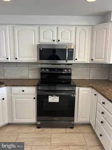 a kitchen with granite countertop a stove a sink and a microwave