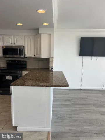 a view of an empty room with wooden floor and a fireplace