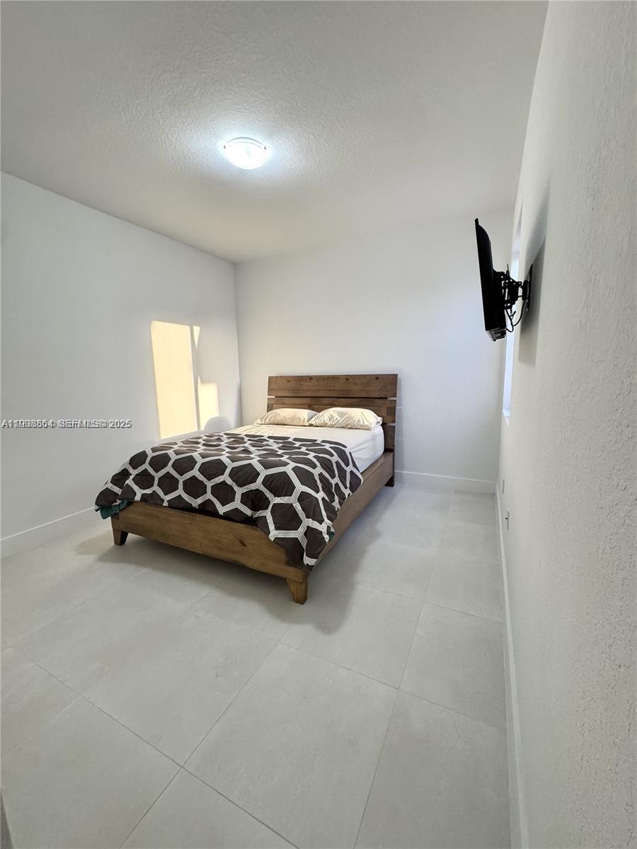 13627 Southwest 157th Court Miami, FL 33196 - Photo 13 of 26 a bedroom with a bed and a night stand