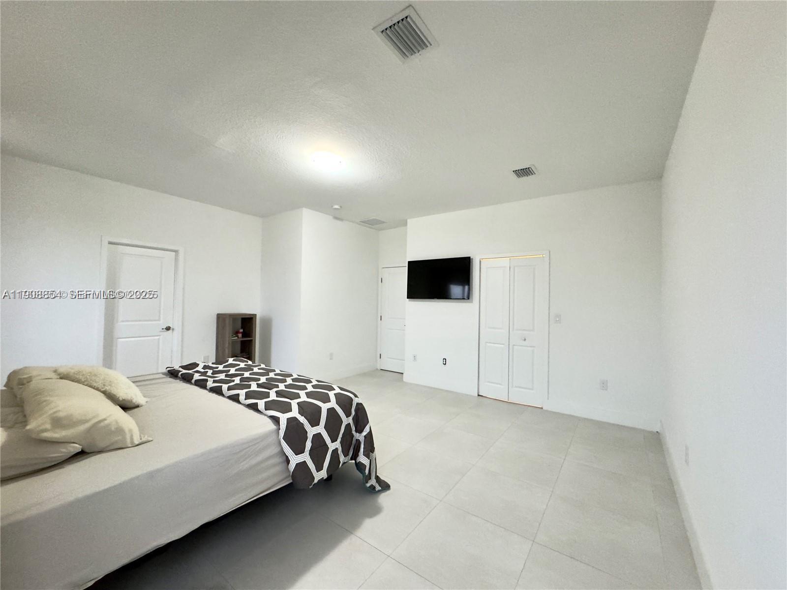 13627 Southwest 157th Court Miami, FL 33196 - Photo 18 of 26 a bedroom with a bed and a tv