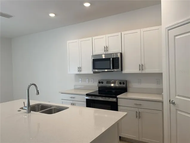 a kitchen with stainless steel appliances granite countertop white cabinets a sink and dishwasher