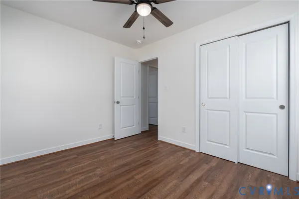 an empty room with wooden floor a ceiling fan and windows