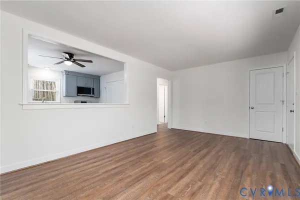 a view of an empty room with wooden floor and a window