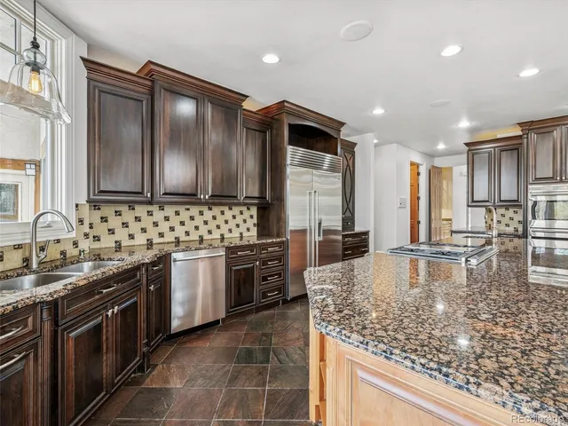 a kitchen with kitchen island granite countertop lots of white cabinets a sink and stainless steel appliances