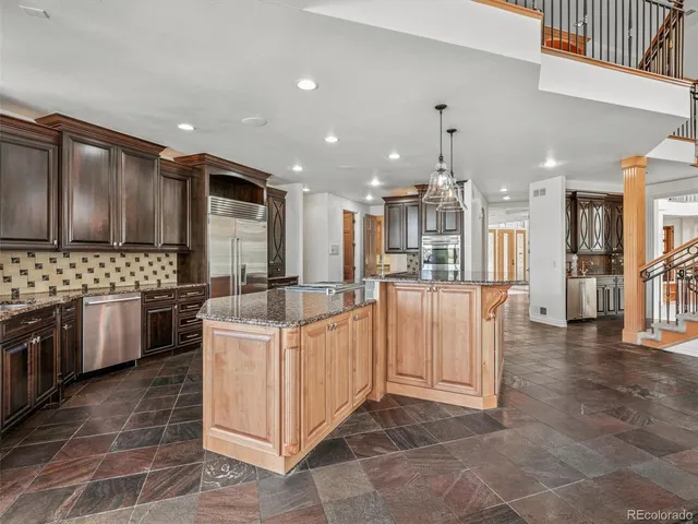a large kitchen with kitchen island a large counter top stainless steel appliances and cabinets