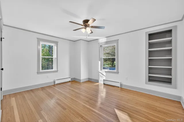 a view of an empty room with a window and wooden floor