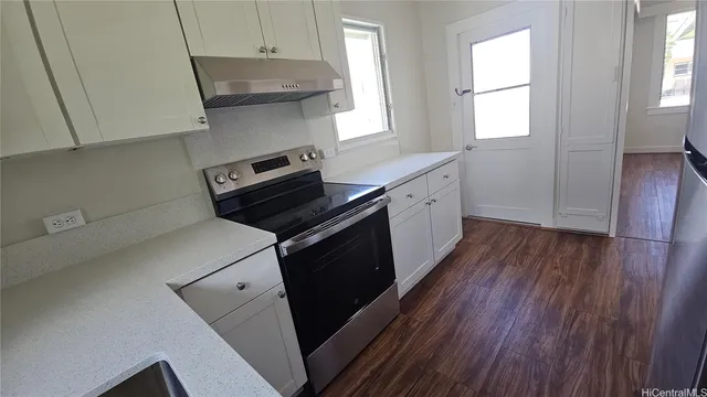 a kitchen with a stove and wooden floor